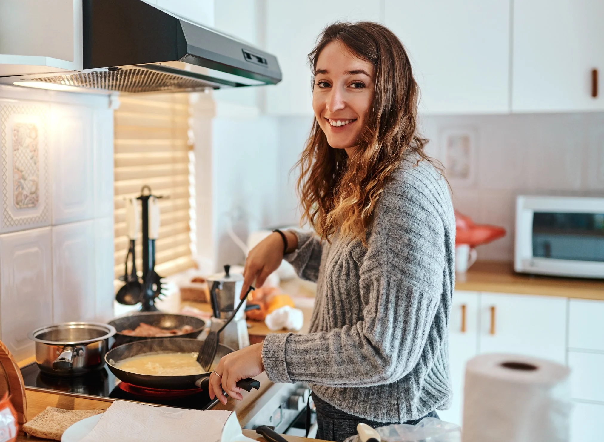 A young woman cooking in a bright kitchen