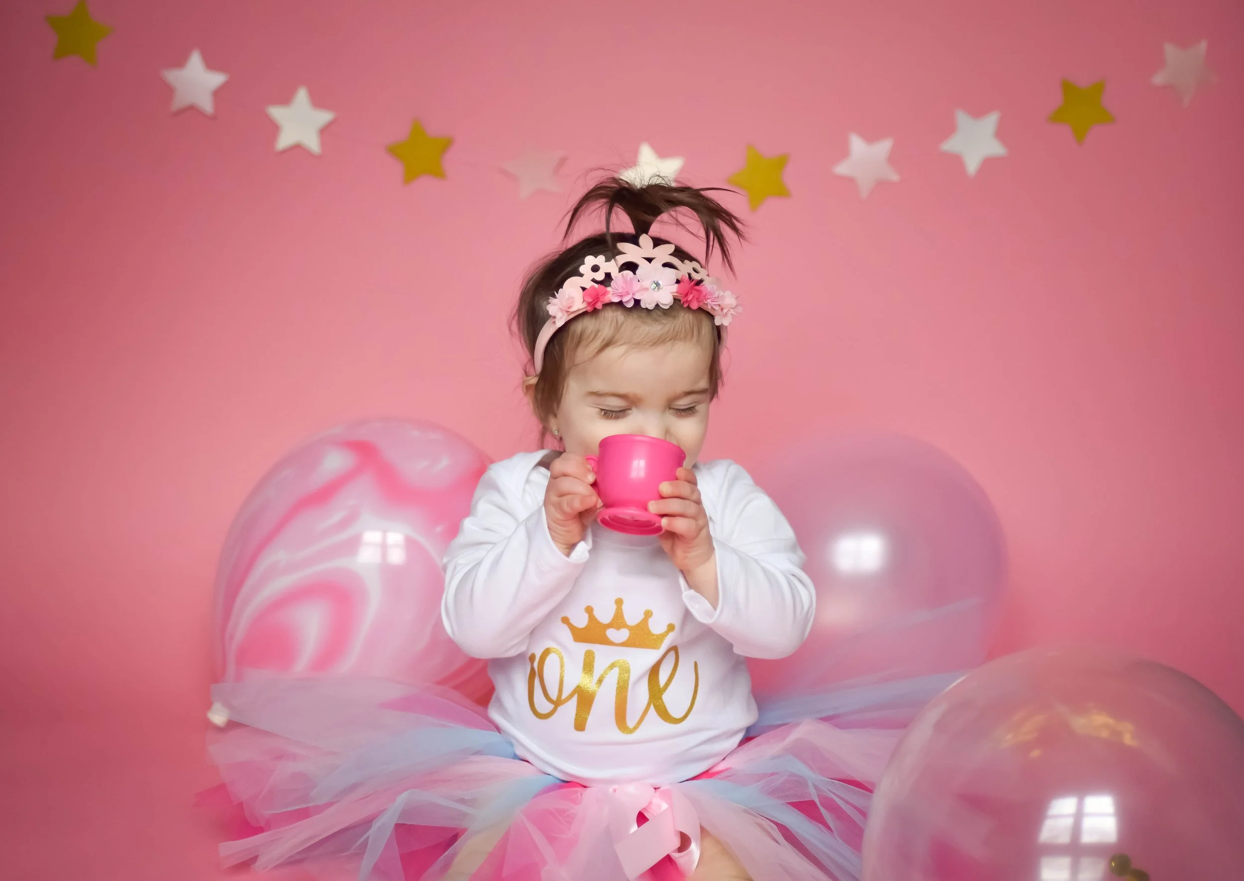 One-yearl old girl celebrating her first birthday in a pink milestone photography session