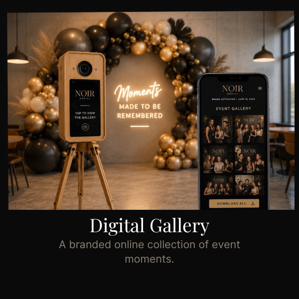 Digital gallery display at event with a smartphone showing event photos and a wooden camera on tripod, with decorative balloons and sign.