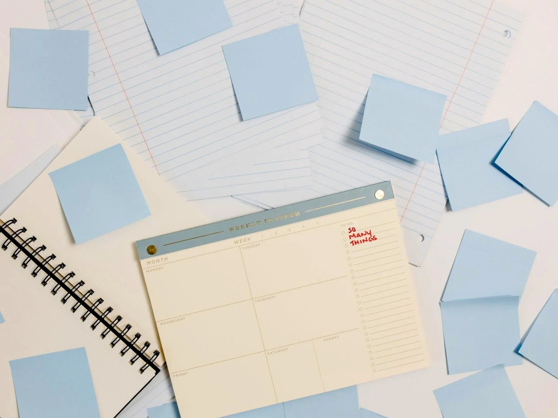 Weekly planner buried in scattered sticky notes reading 'so many things,' capturing work that's grown hard to track.
