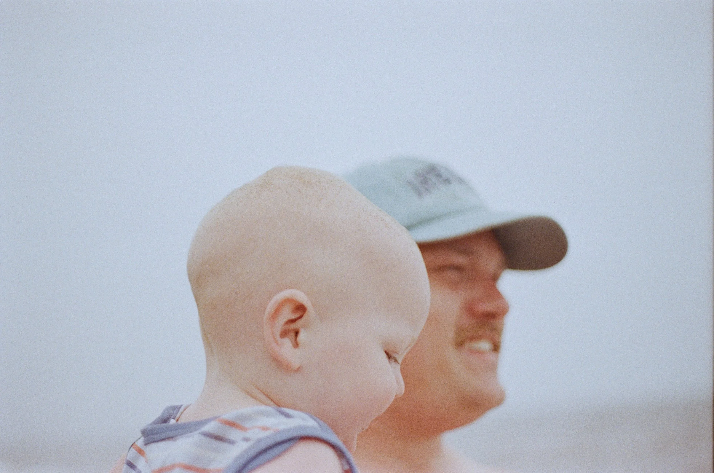 Close up of a side-profile of a man holding a toddler smiling.