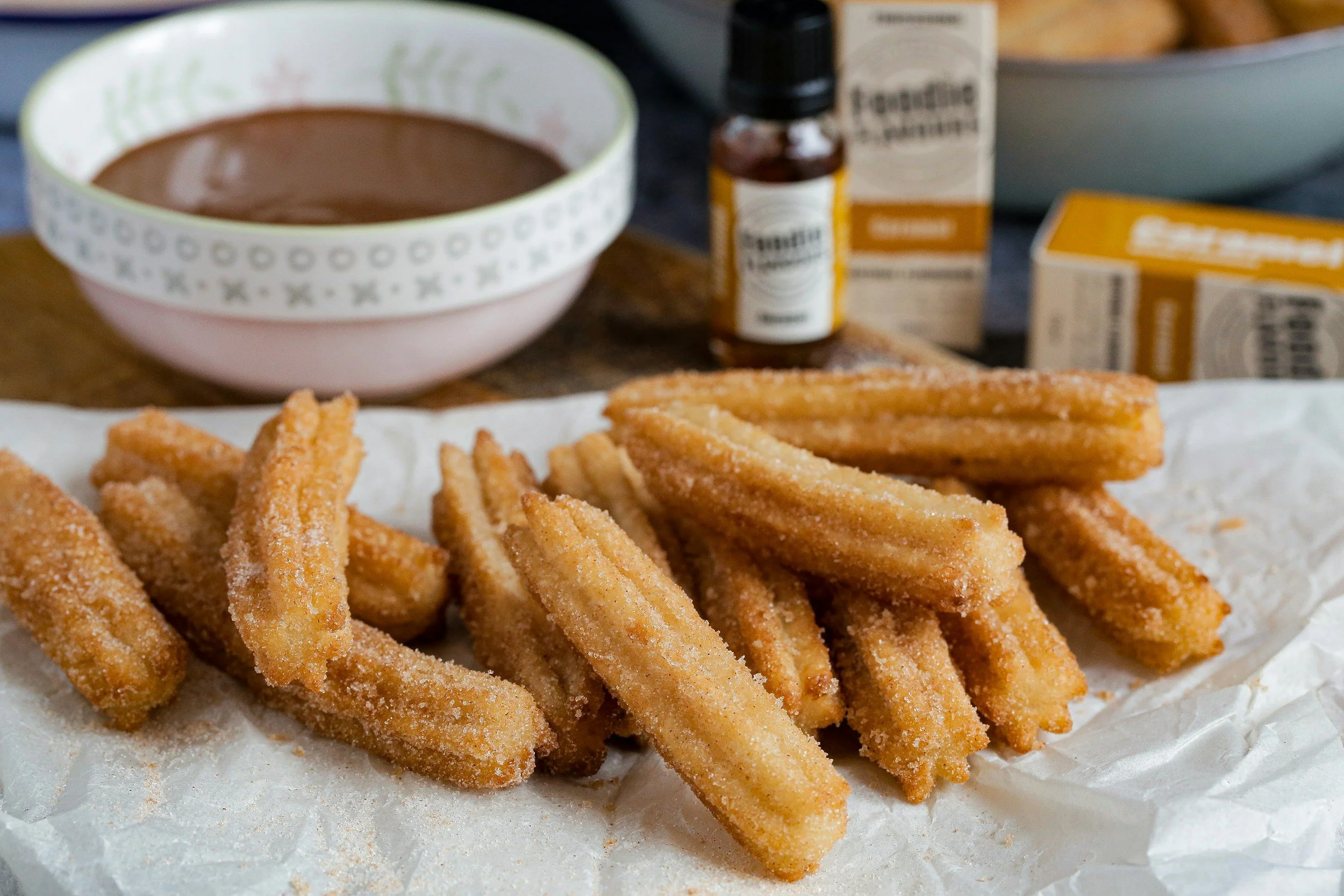Golden cinnamon-sugar churros served with a bowl of warm chocolate dipping sauce