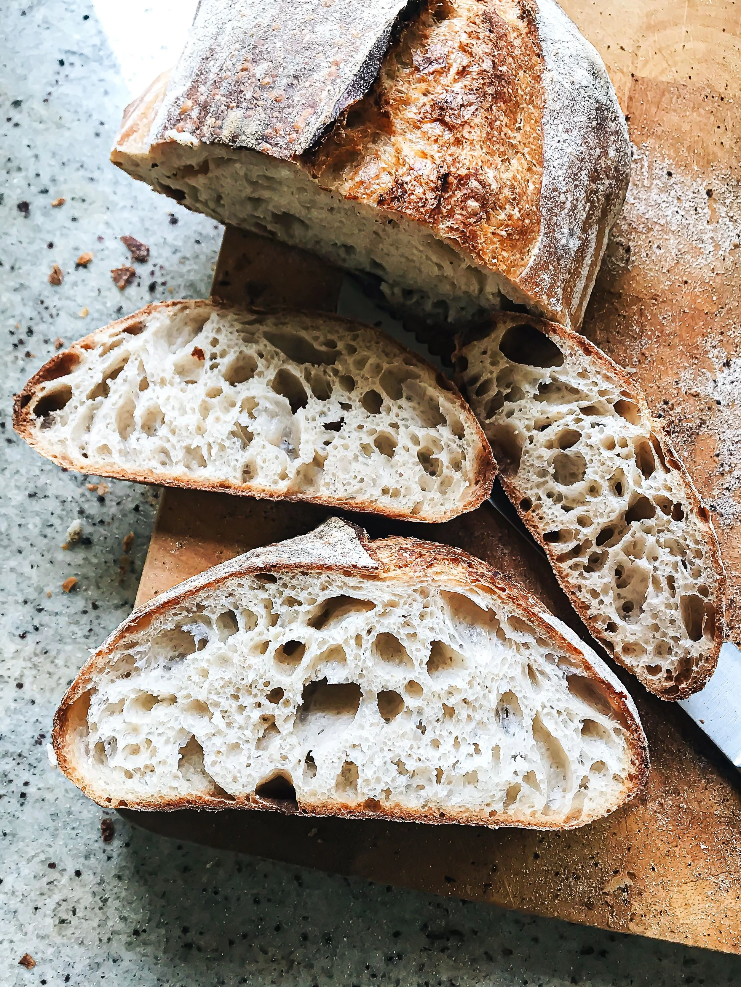 Sliced sourdough bread loaf with a crisp, floured crust and open airy crumb, used for Front Porch Social's Sourdough Slider Bar catering in Northern Colorado