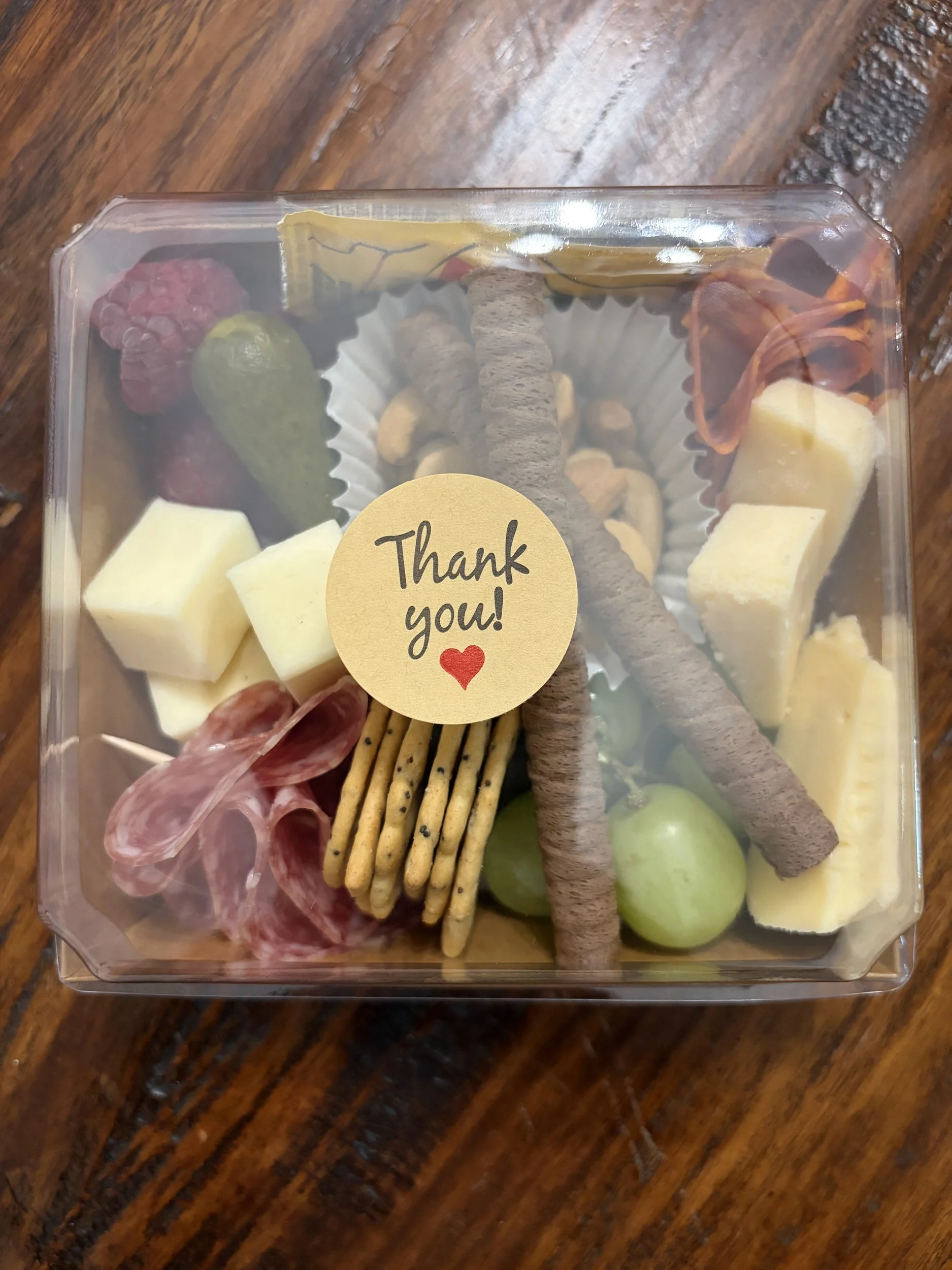 Individual charcuterie box with cheese cubes, salami, pretzel sticks, chocolate-dipped pretzels, grapes and a Thank you sticker, made as a party favor by Front Porch Social