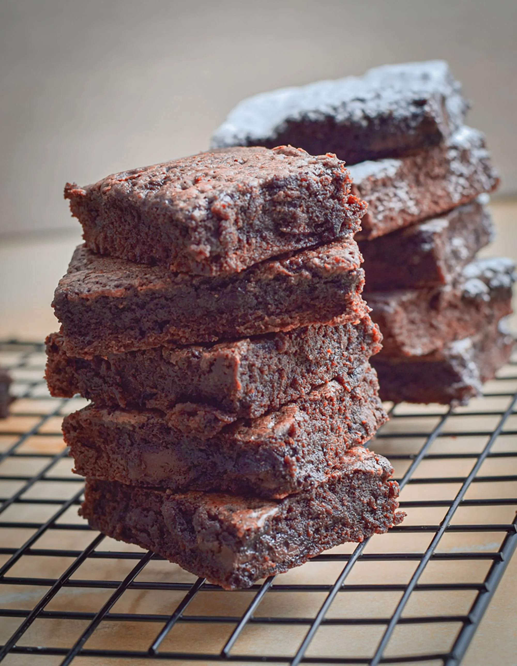 Stacked squares of fudgy chocolate brownies cooling on a wire rack