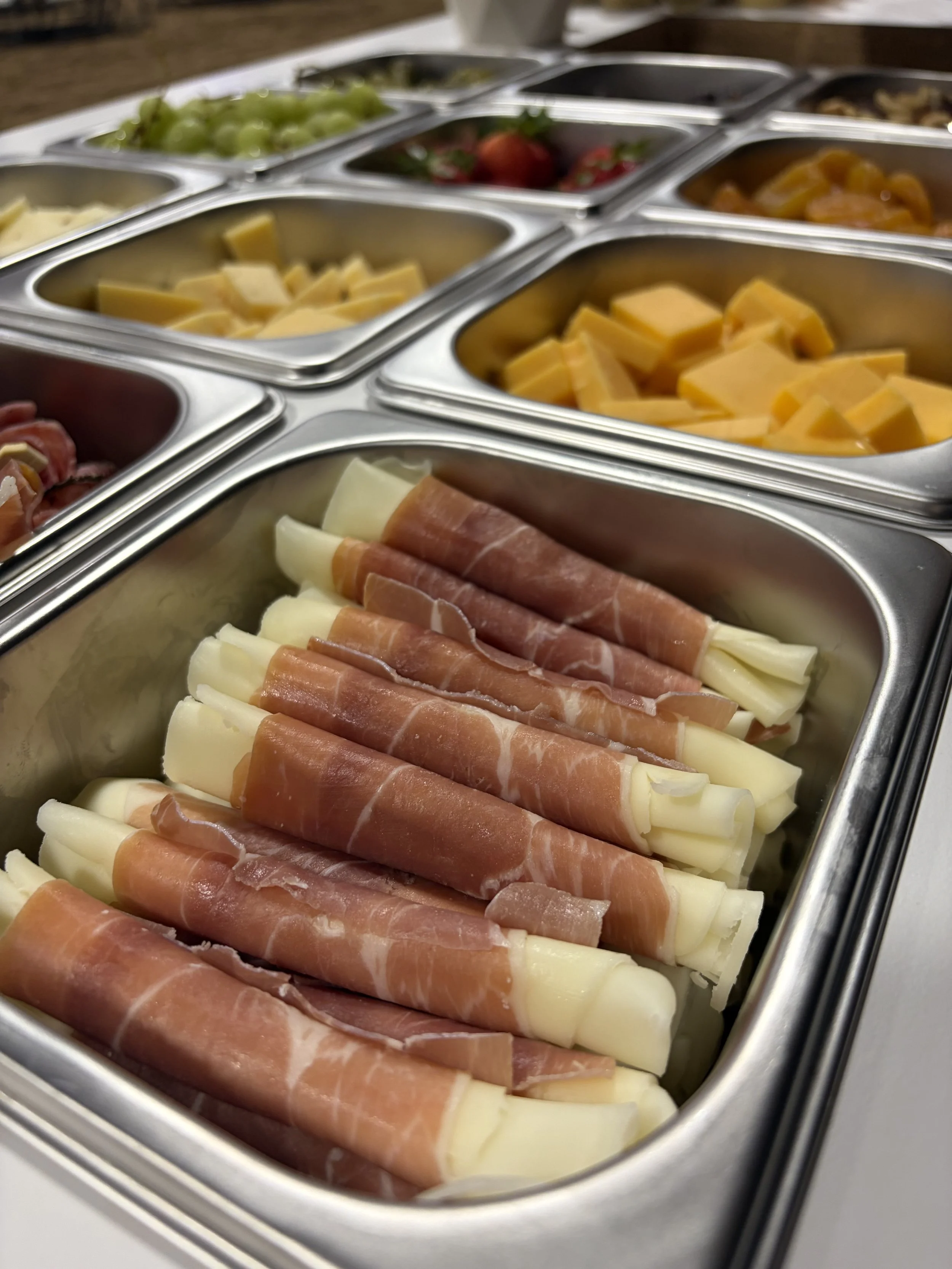 Mobile snack cart for office holiday parties in Northern Colorado, with cubed cheddar, fresh strawberries, grapes, and prosciutto-wrapped cheese sticks