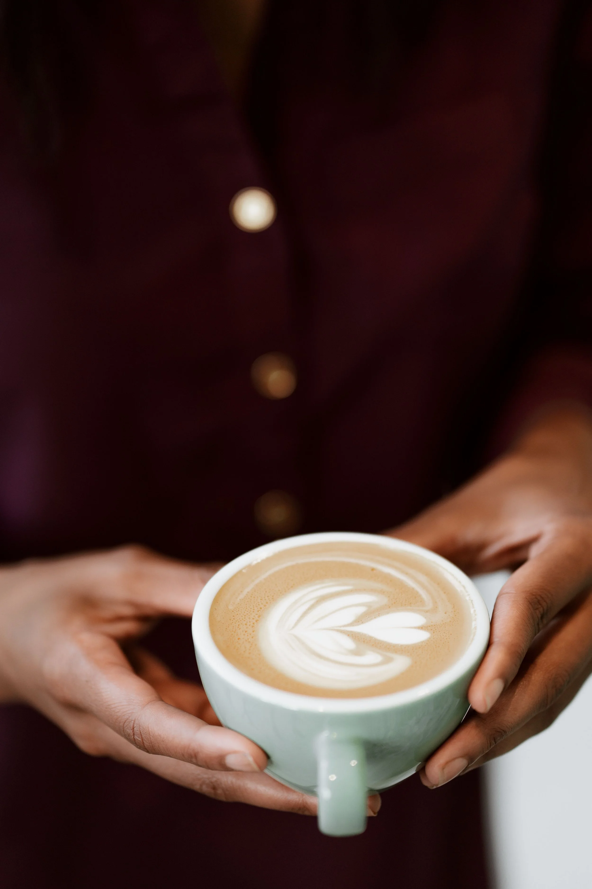 Person holding a cup of latte with heart-shaped foam art