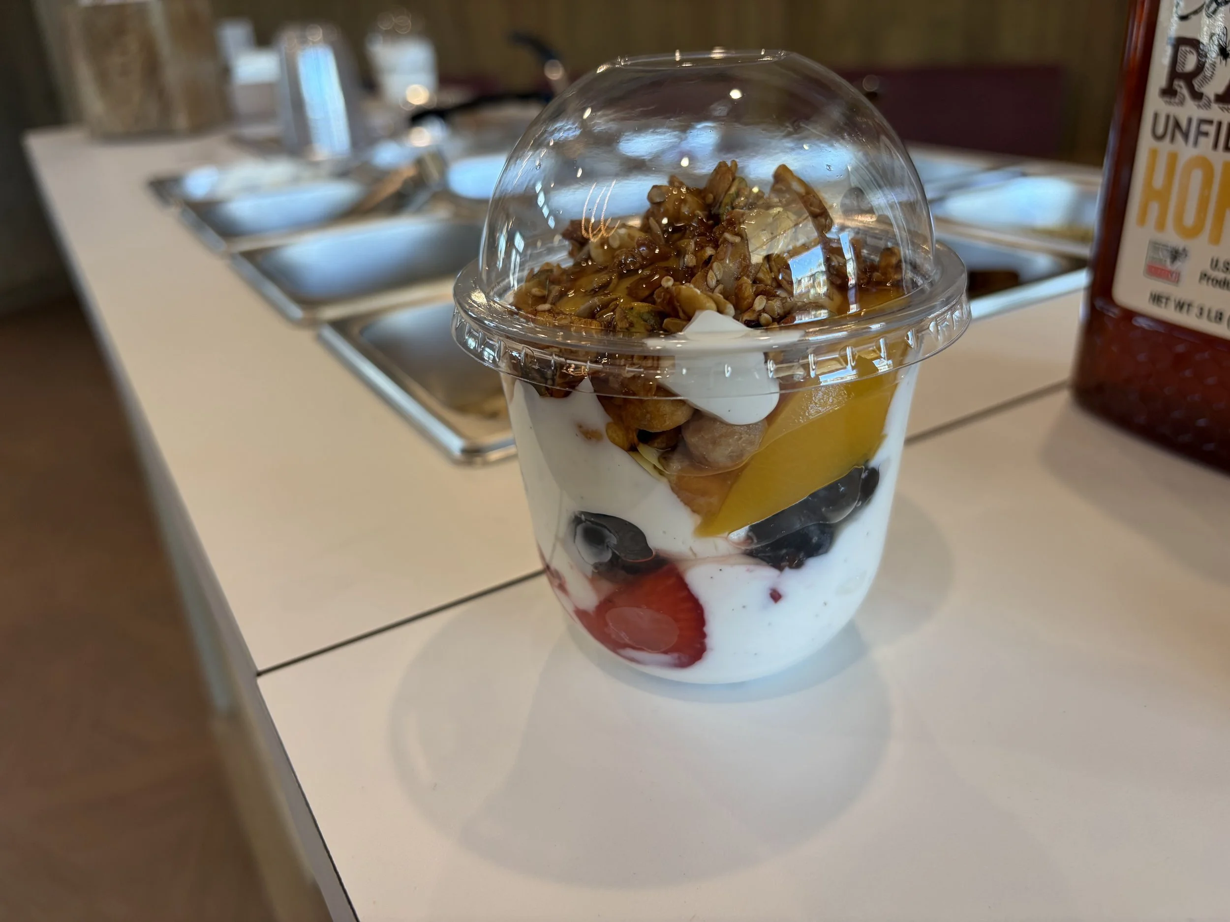 Greek yogurt parfait cup layered with strawberries, blueberries, peaches and honey granola from Front Porch Social's Protein Power Bar