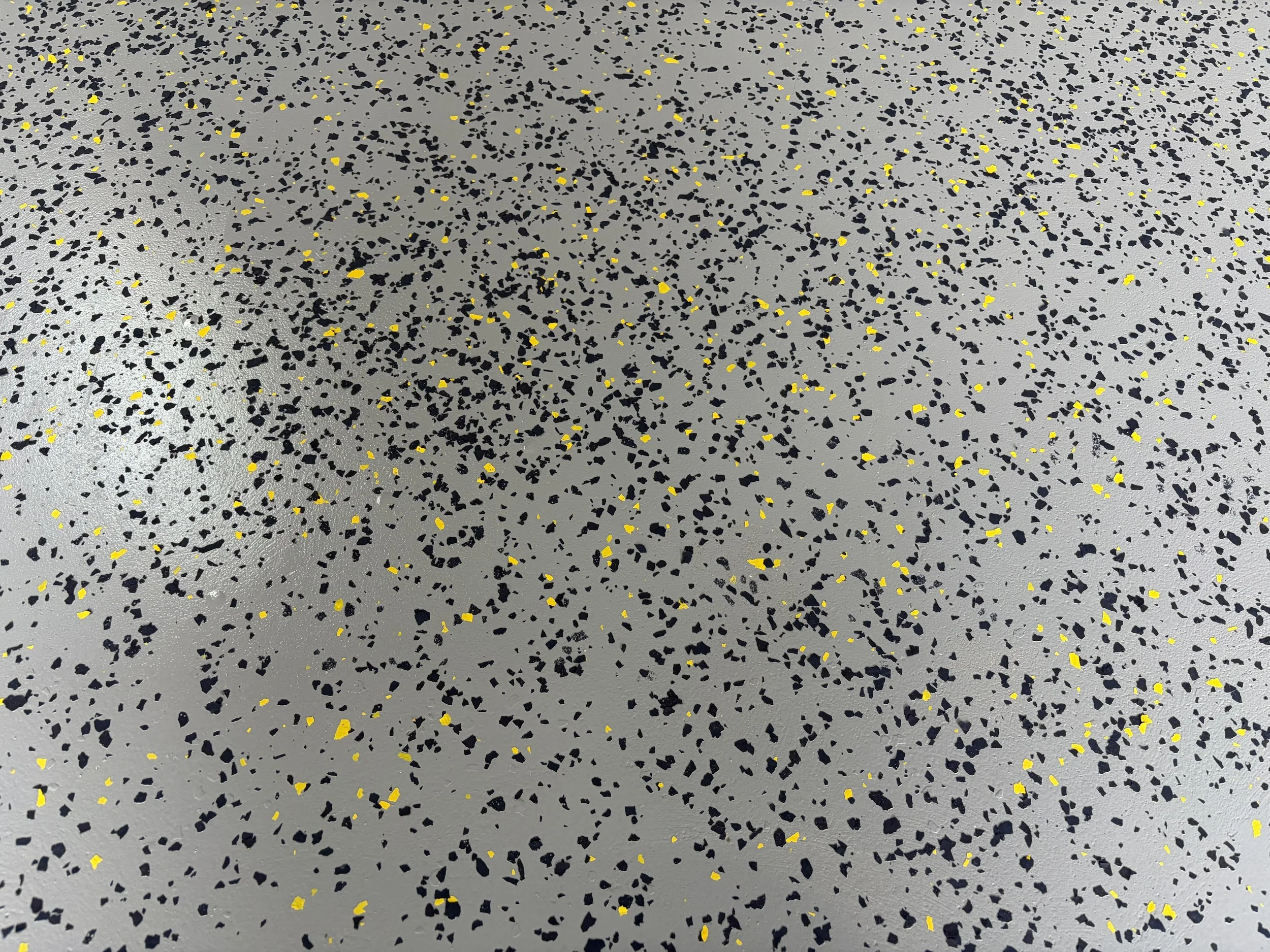 Gray floor with black and yellow speckled pattern.