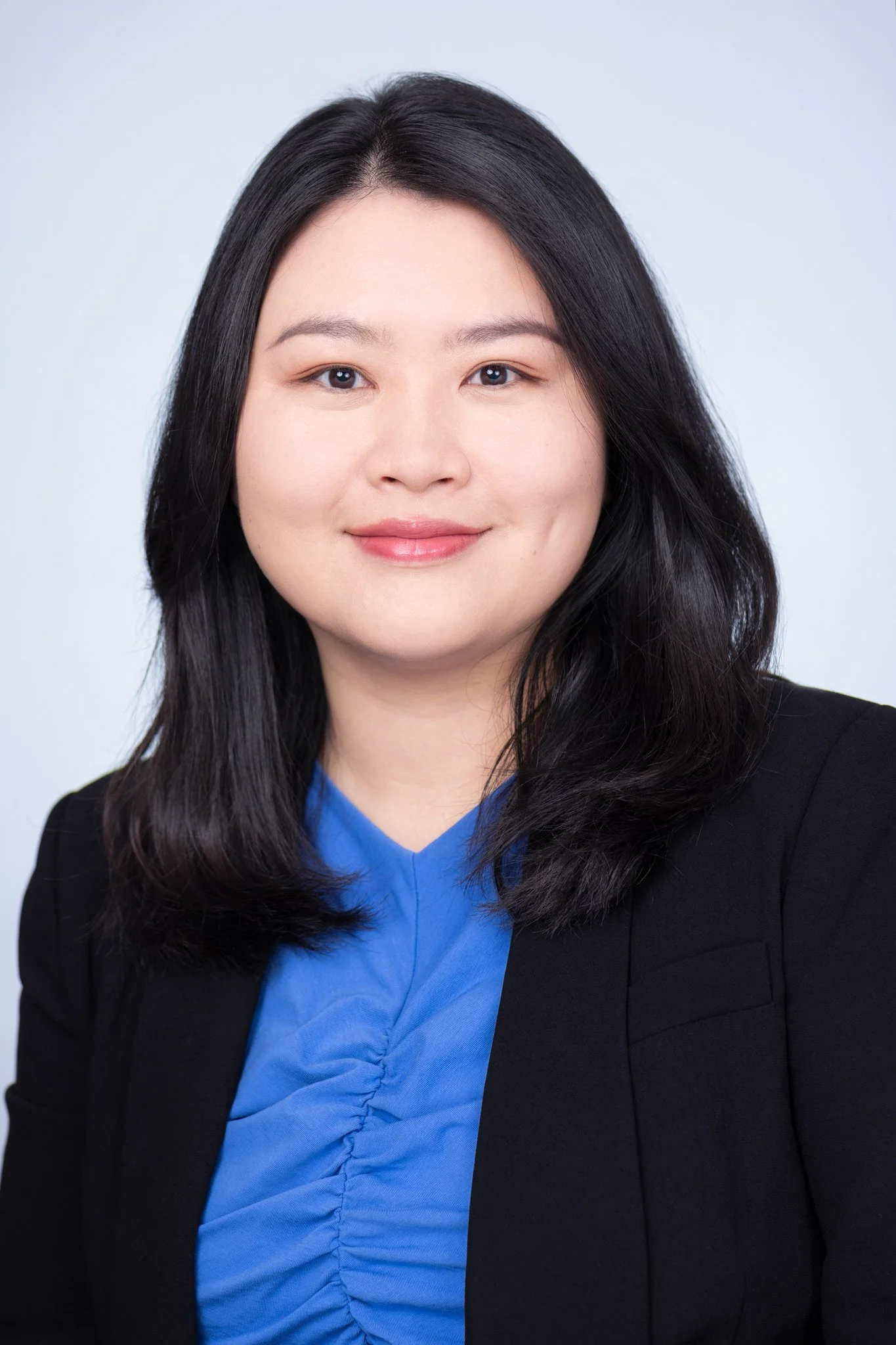 Headshot of Anna Tao, A woman with medium-length black hair, wearing a blue blouse and black blazer, smiling