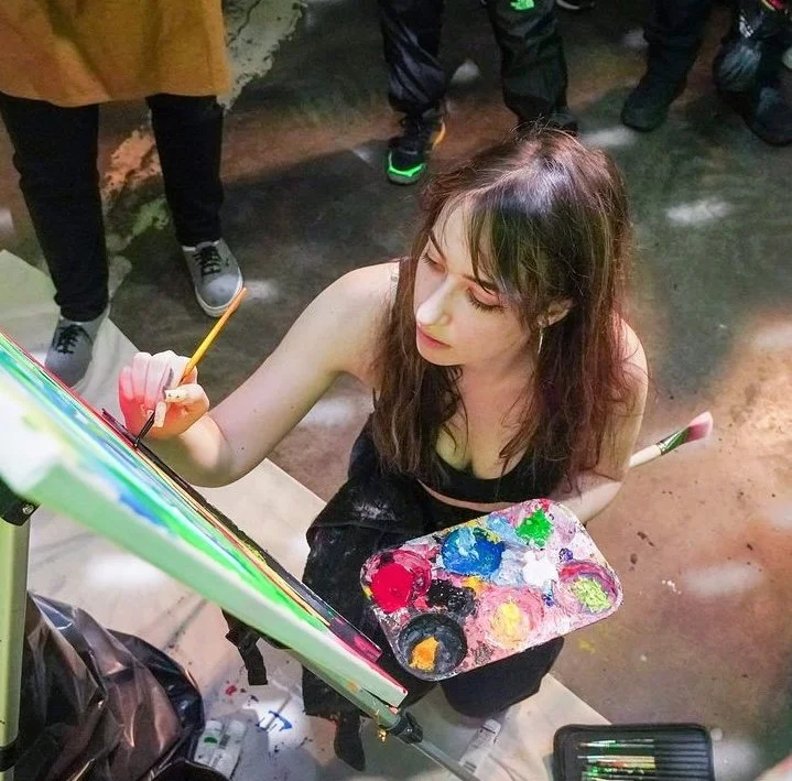 Young woman painting on a canvas with a palette of colors.