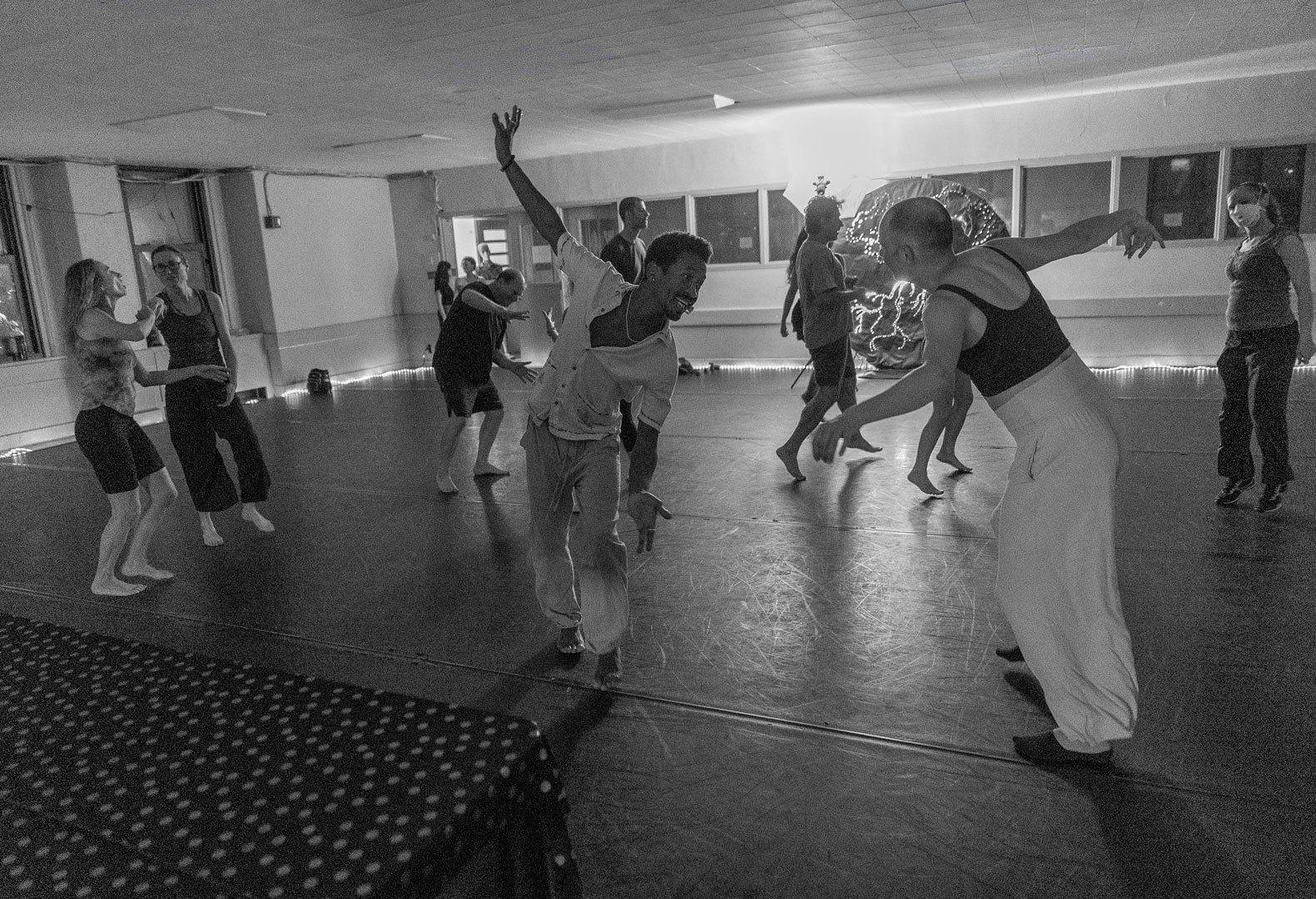 Group of dancers practicing expressive movement in a mirrored studio.