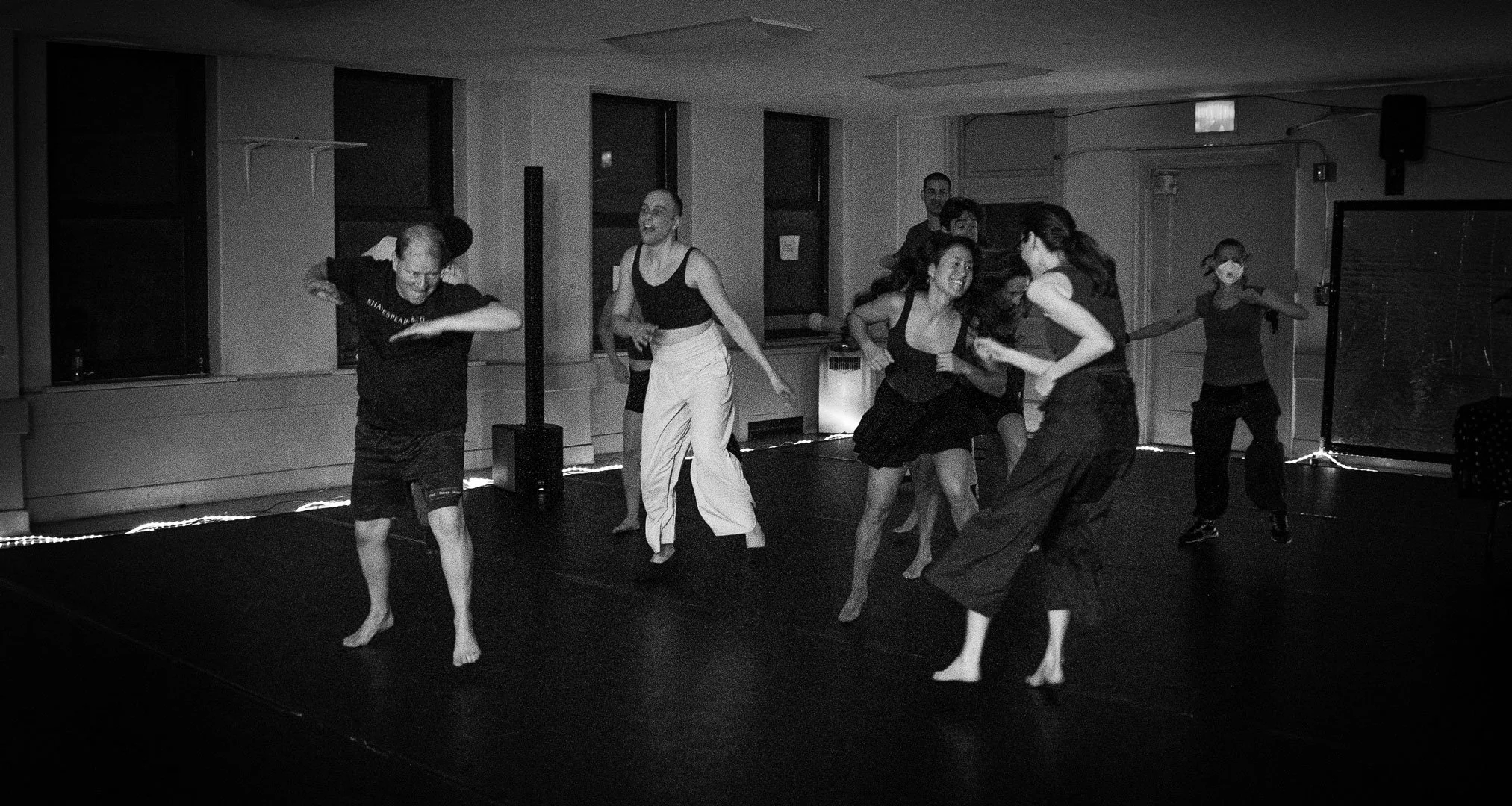 Group of dancers rehearsing barefoot in a studio.
