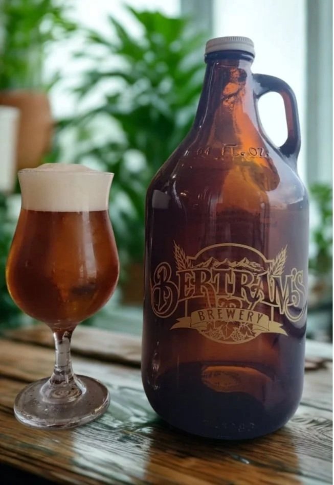 A glass of beer with a foamy head and a large brown growler with the logo 'Bertram's Salmon Valley Brewery' on the bar