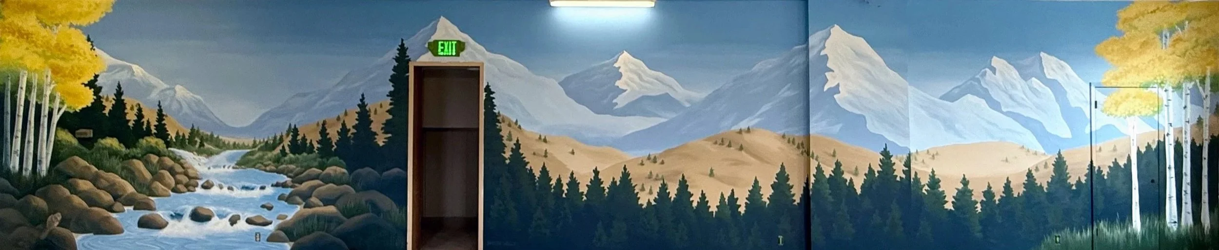 A nature mural with mountains, trees, a river, and a cloudy sky. A doorway is in the center of the mural, and a green exit sign is above it.