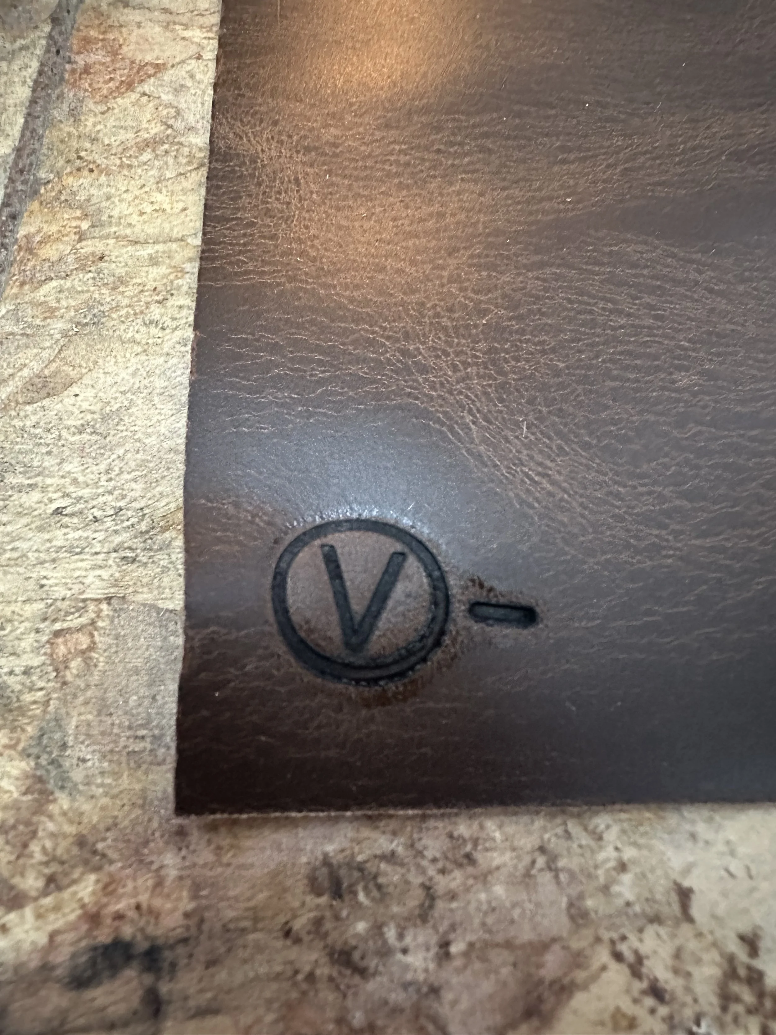 Close-up of a metal surface with a Volkswagen logo engraved on it, placed on a textured, rough surface.