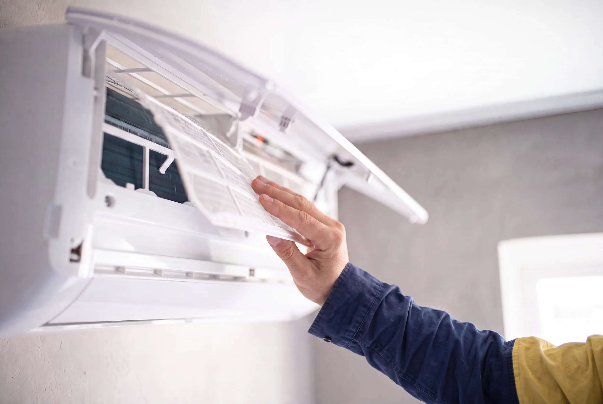 A worker is installing air conditioning or HVAC unit mounted on the wall.