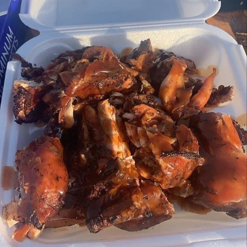 Barbecue chicken pieces with sauce in a foam takeout container.