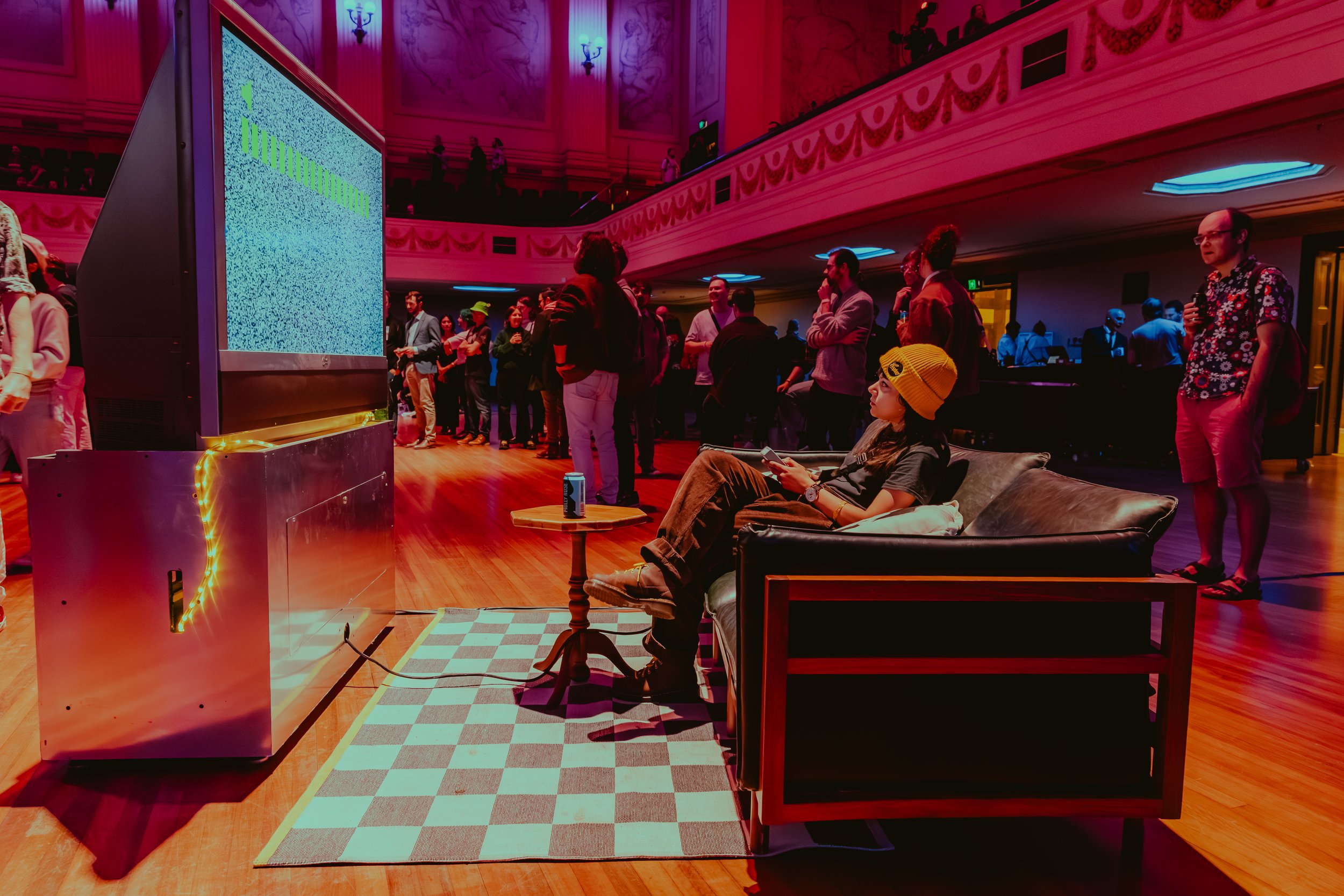 Immersive lounge setting in large event, attendee plays with interactive art on a large rear projection TV