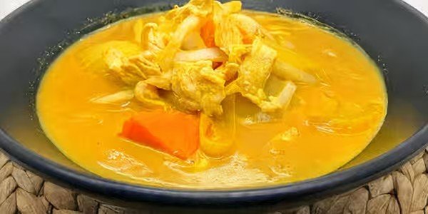 A bowl of chicken and vegetable soup with shredded chicken, carrots, and egg.