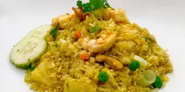 Plate of shrimp fried rice garnished with a cucumber slice and cilantro.