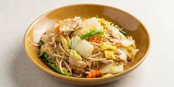 A bowl of Asian-style noodle stir-fry with vegetables and chicken.