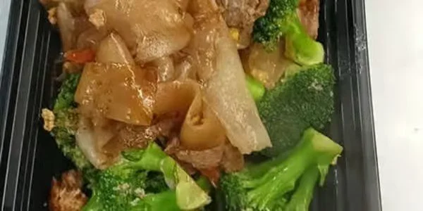 Steamed broccoli with beef and vegetables in a black tray.