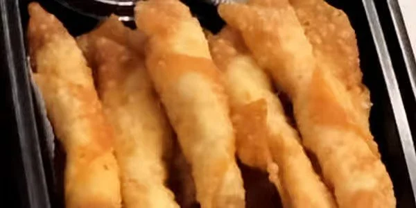 Close-up of breaded and fried fish sticks in a black tray.