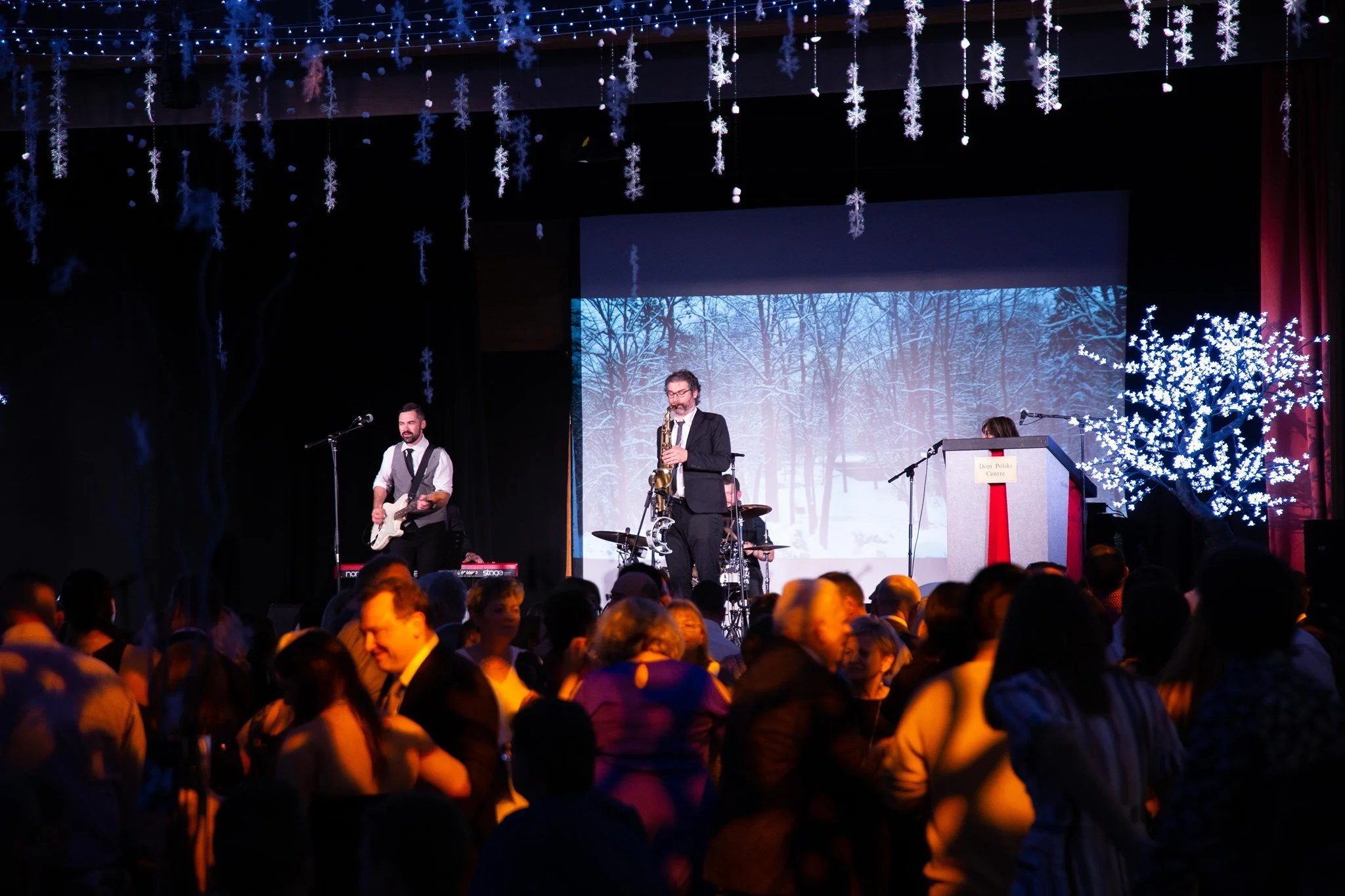 Band with guitar and saxophone performing at a winter-themed event at Dom Polski.