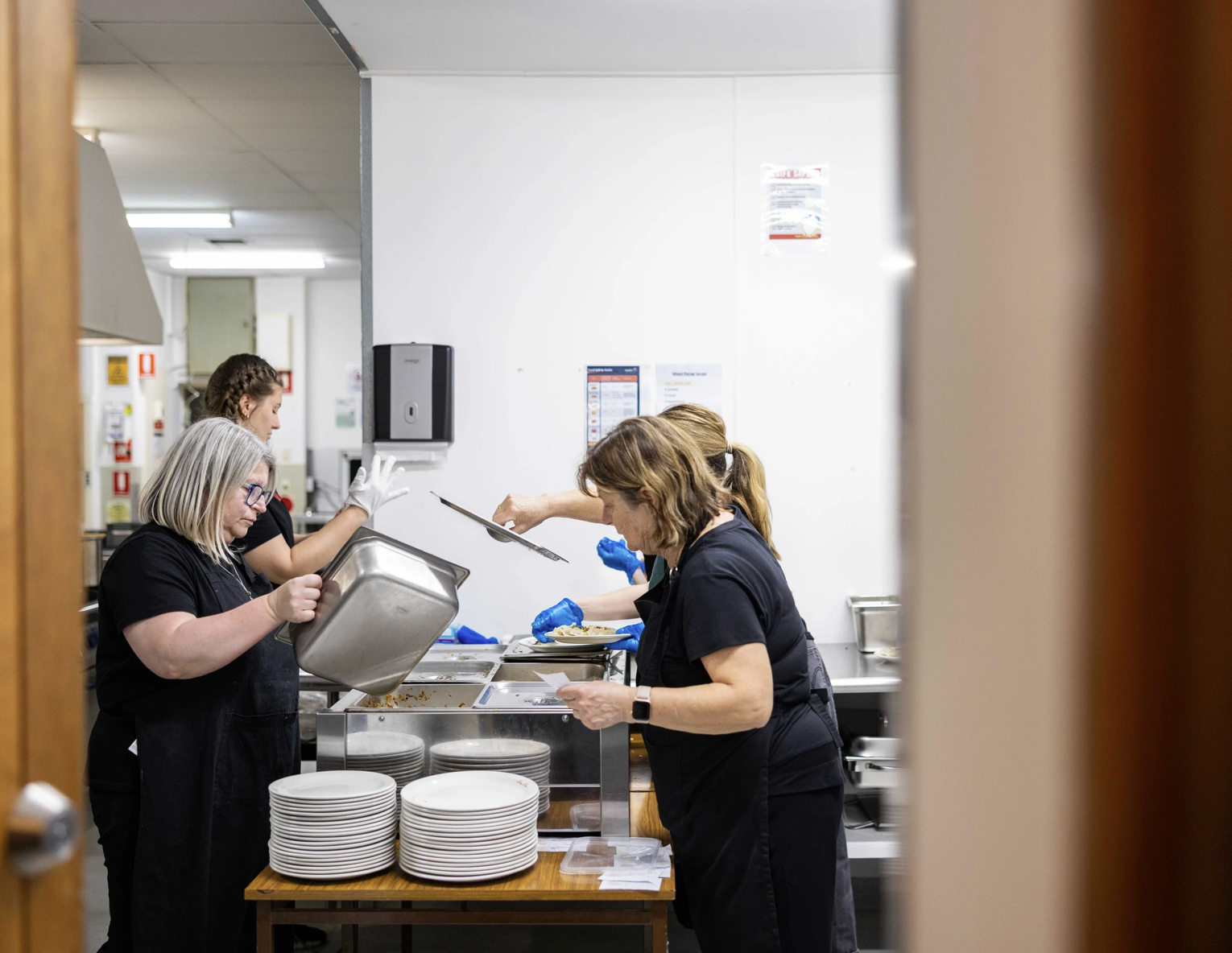 Volunteers serving food from the kitchen at Dom Polski Centre Adelaide.