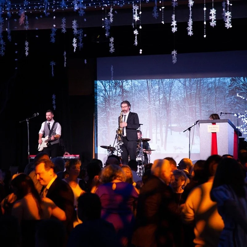 Live band performing at a winter-themed event at Dom Polski, with guests dancing.