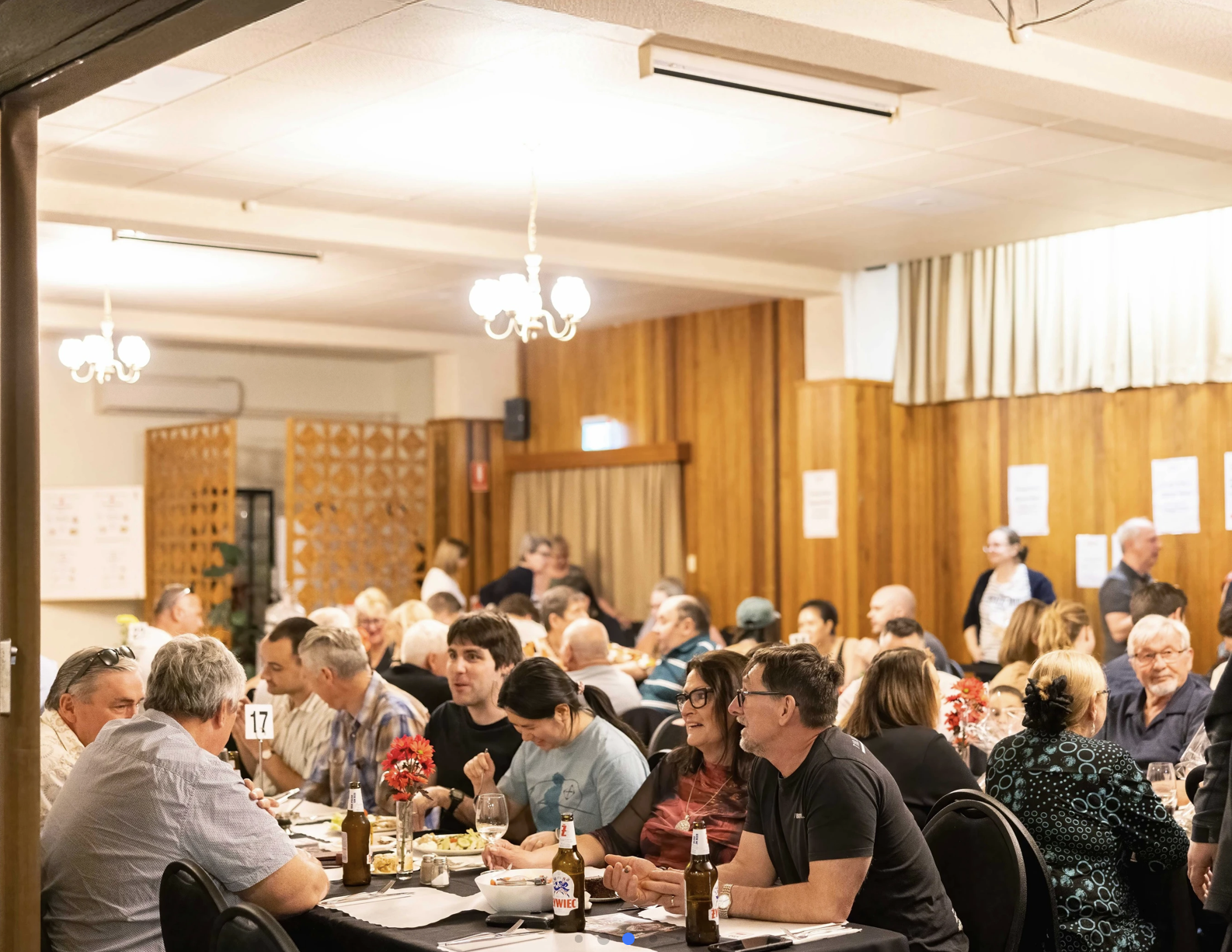 Guests sharing a meal and Polish beer at long tables at Dom Polski Adelaide.