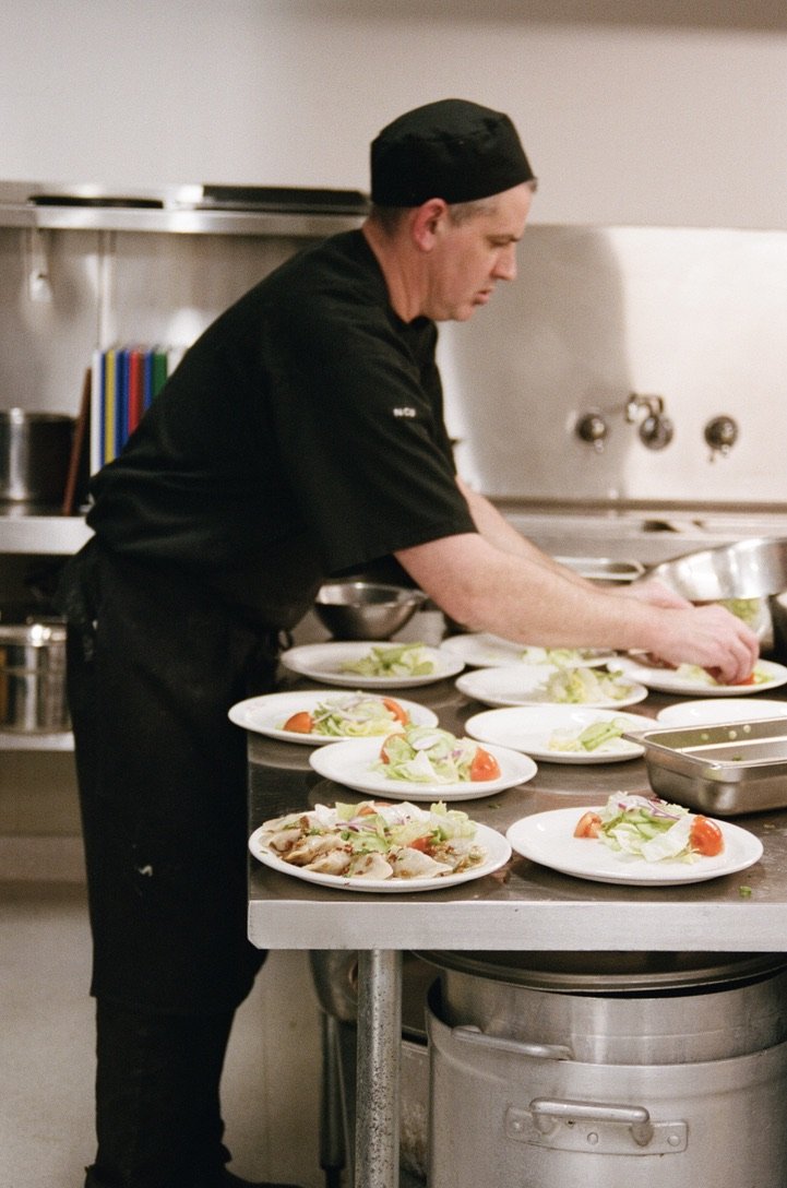 Chef plating salads and entrées in the Dom Polski kitchen.