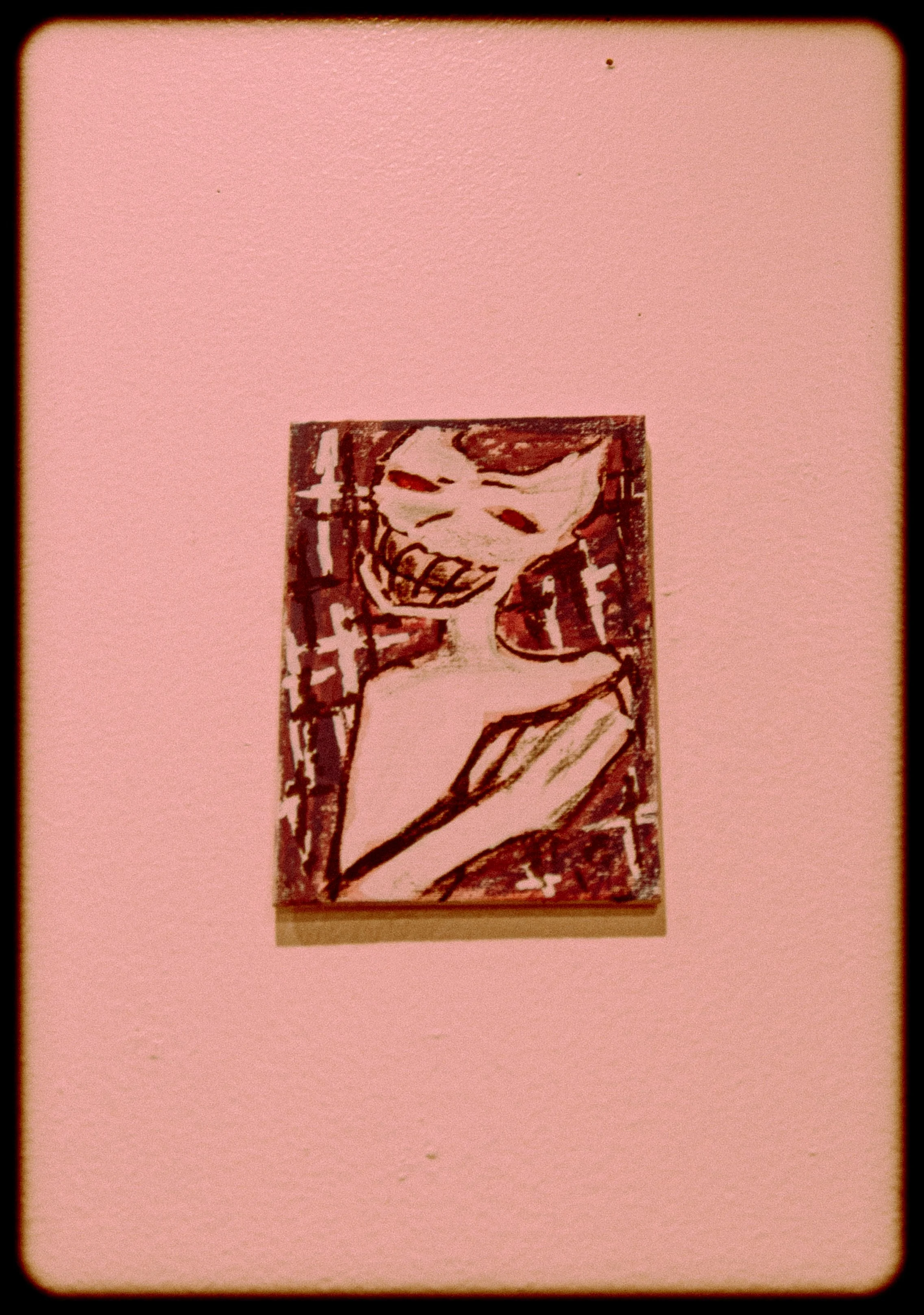 A black and white drawing of a clown with a big smile, wearing a ruffled collar, with the year 2018 written vertically on the left side, mounted on a pink wall.