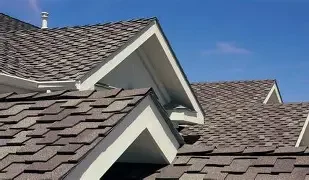 Close-up of rooftops with brown shingles and white trim on a clear day.