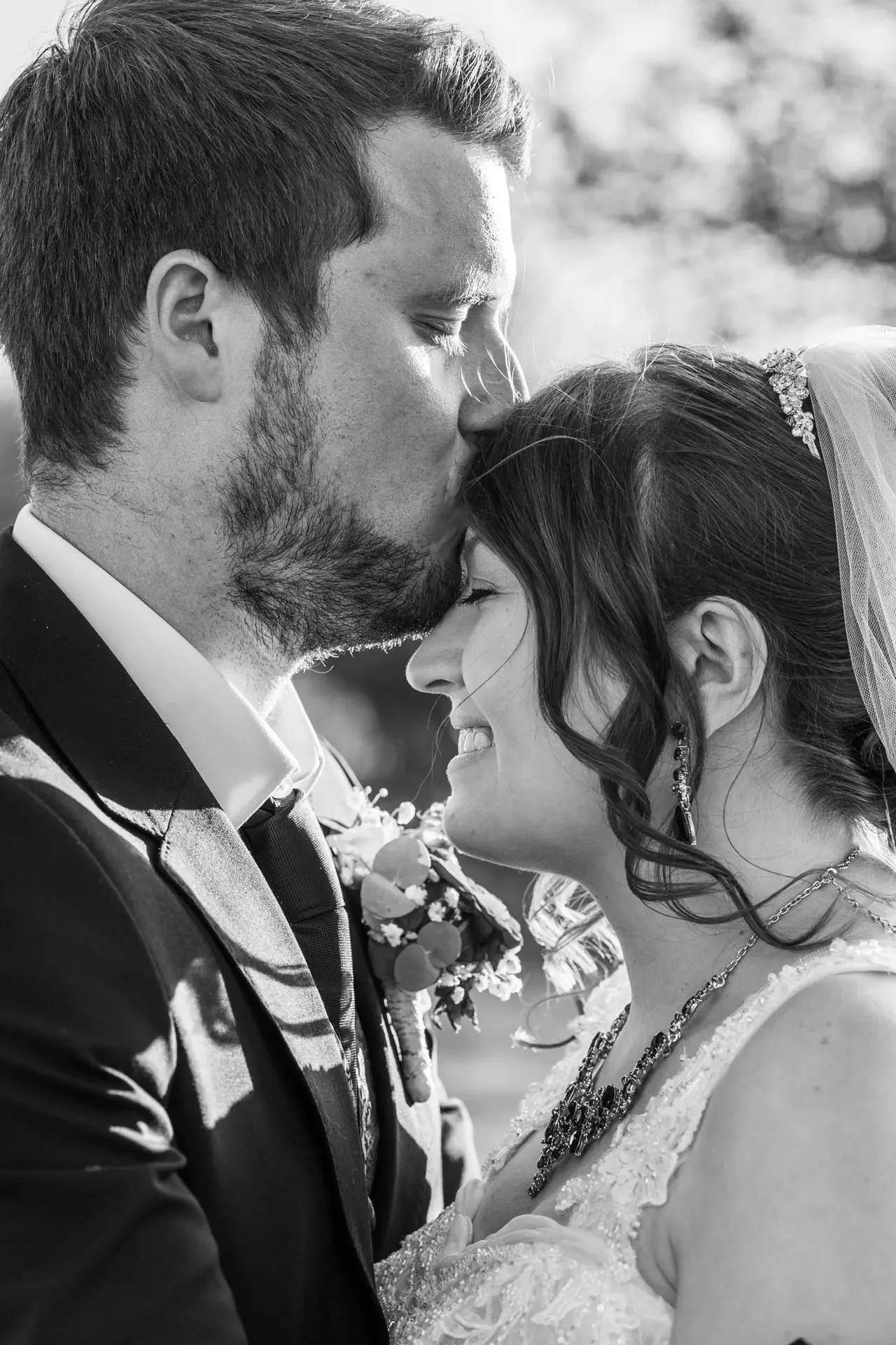 Ein Brautpaar auf ihrer Hochzeit im Fichtelgebirgshof, er küsst sie liebevoll auf die Stirn. Ungestellte Aufnahme einer Hochzeitsreportage.