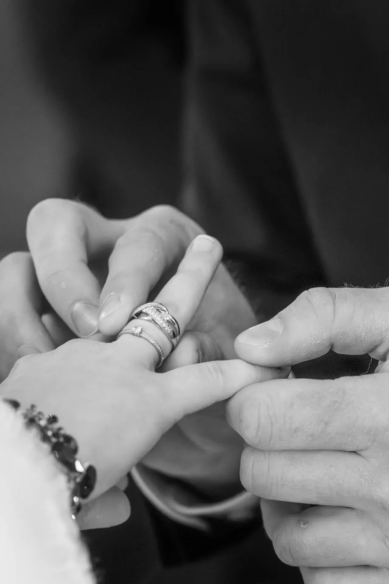 Nahaufnahme von zwei Händen, die sich im Tausch eines Rings befinden. Die Hände tragen mehrere Ringe, ein Armband und haben gepflegte Nägel. Trauung in der Kirche Gefrees.