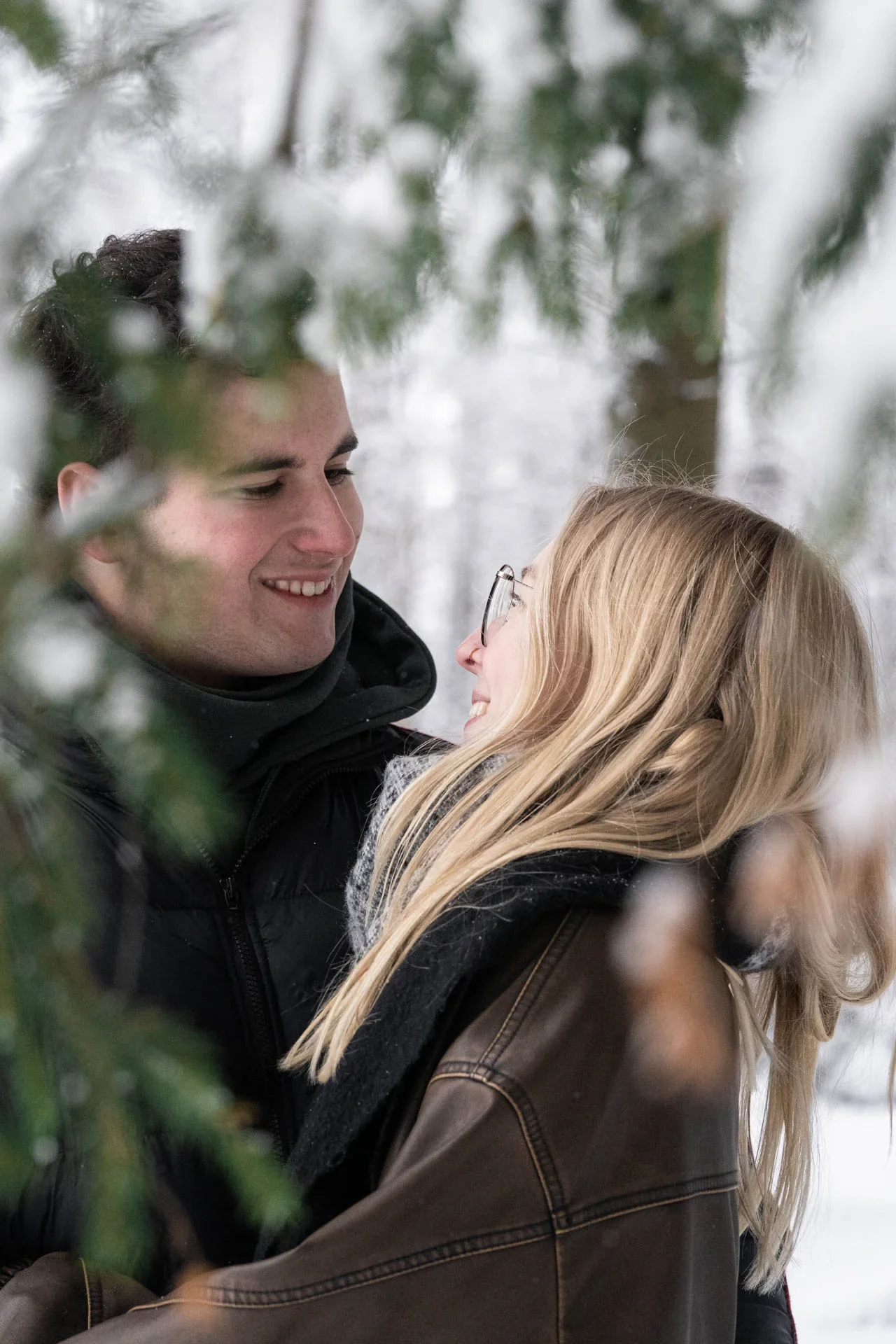 Kreative Bildgestaltung beim Paarshooting im Winterwald durch verschneite Äste fotografiert.