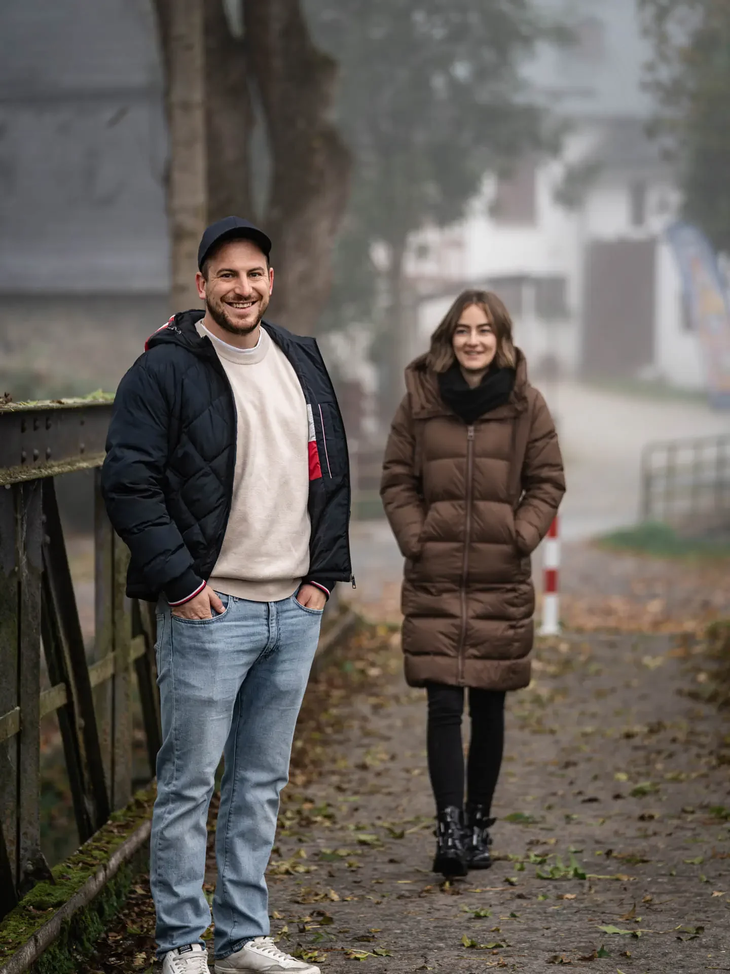 Entspannter Spaziergang beim Paarshooting auf einer Brücke im sanften Nebellicht.