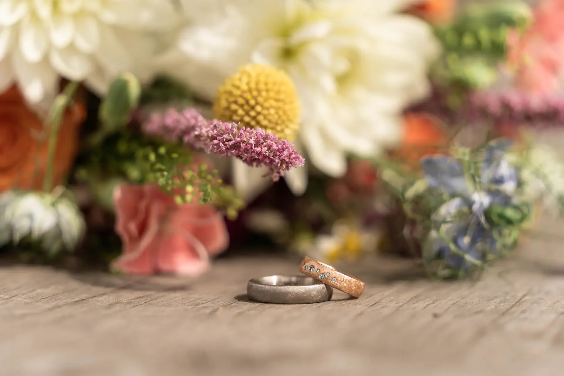 Kreative Detailfotografie der Eheringe auf Holzuntergrund am Hochzeitstag im Saale-Orla-Kreis.