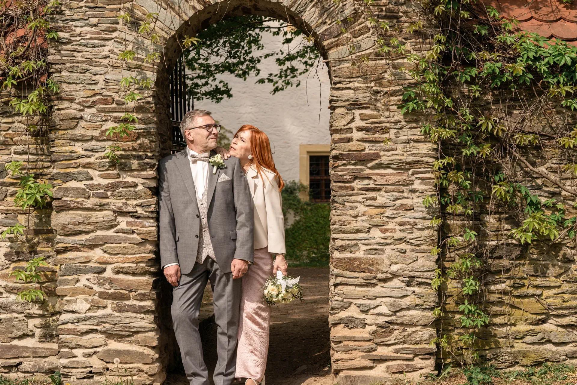 Brautpaar steht verliebt in einem historischen Steinbogen – natürliche Hochzeitsfotografie in Chemnitz von Dominik Lüdtke.