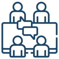 Four people in a meeting room, two are sitting at a table, and two are standing behind them, engaged in discussion.