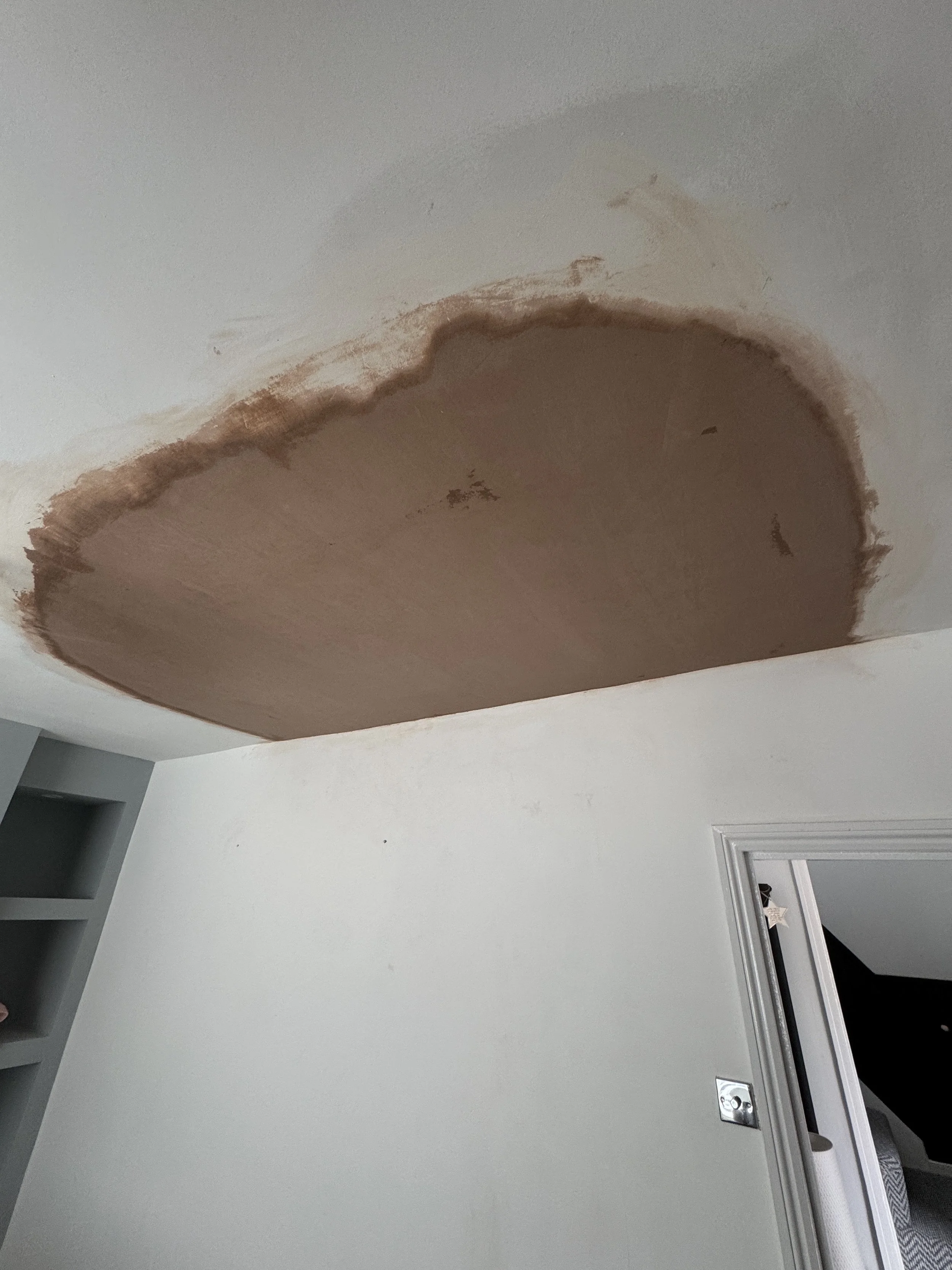 Ceiling with water damage and peeling paint in a room.