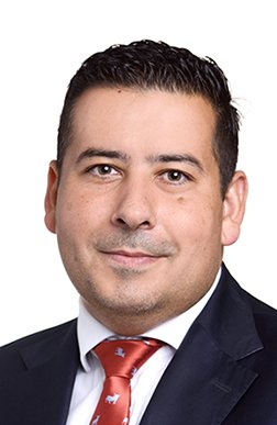 Porträt eines Mannes in formeller Kleidung, dunkles Hemd, rote Krawatte, heller Hintergrund