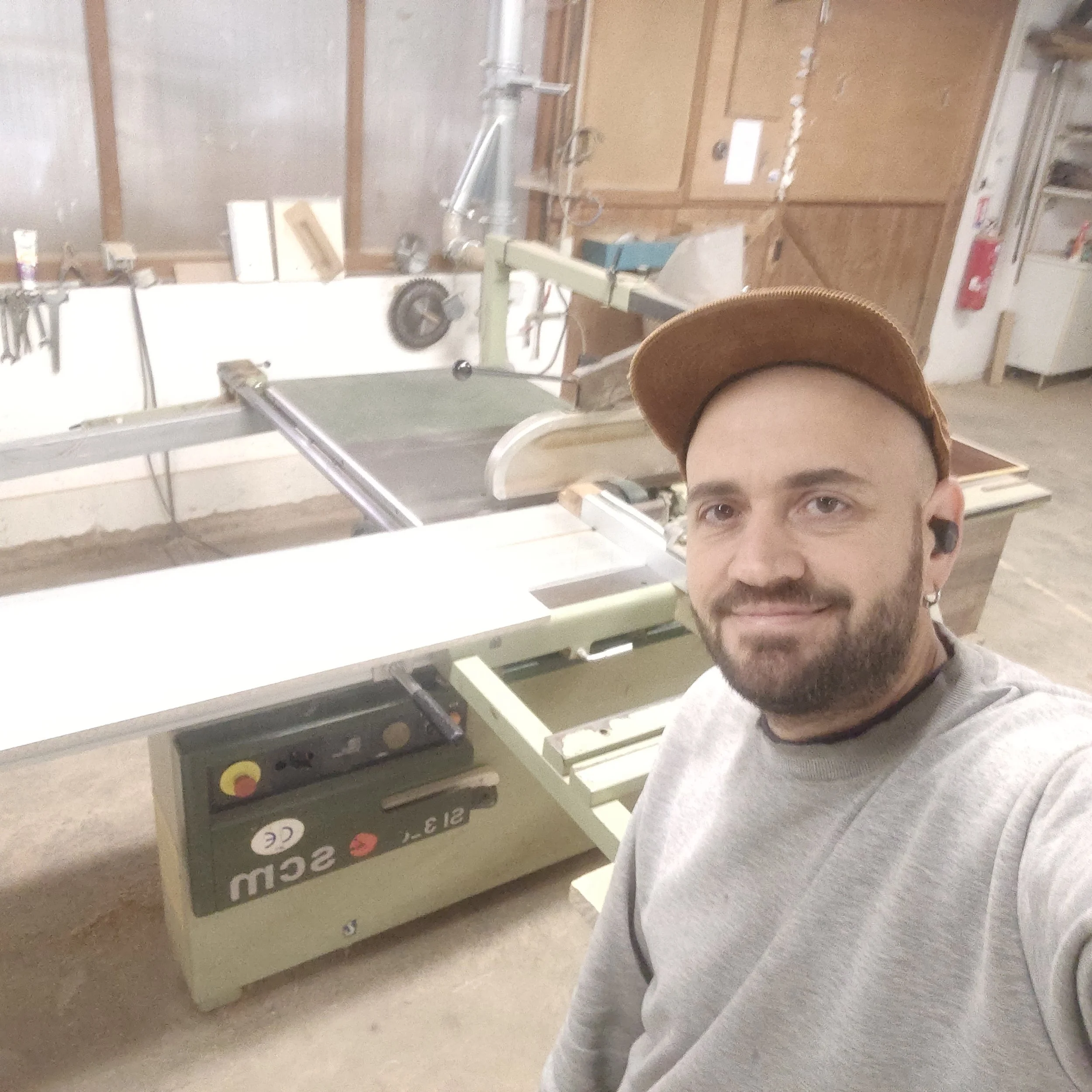 Personne portant une casquette de baseball à côté d'une machine ou un outil en atelier.
