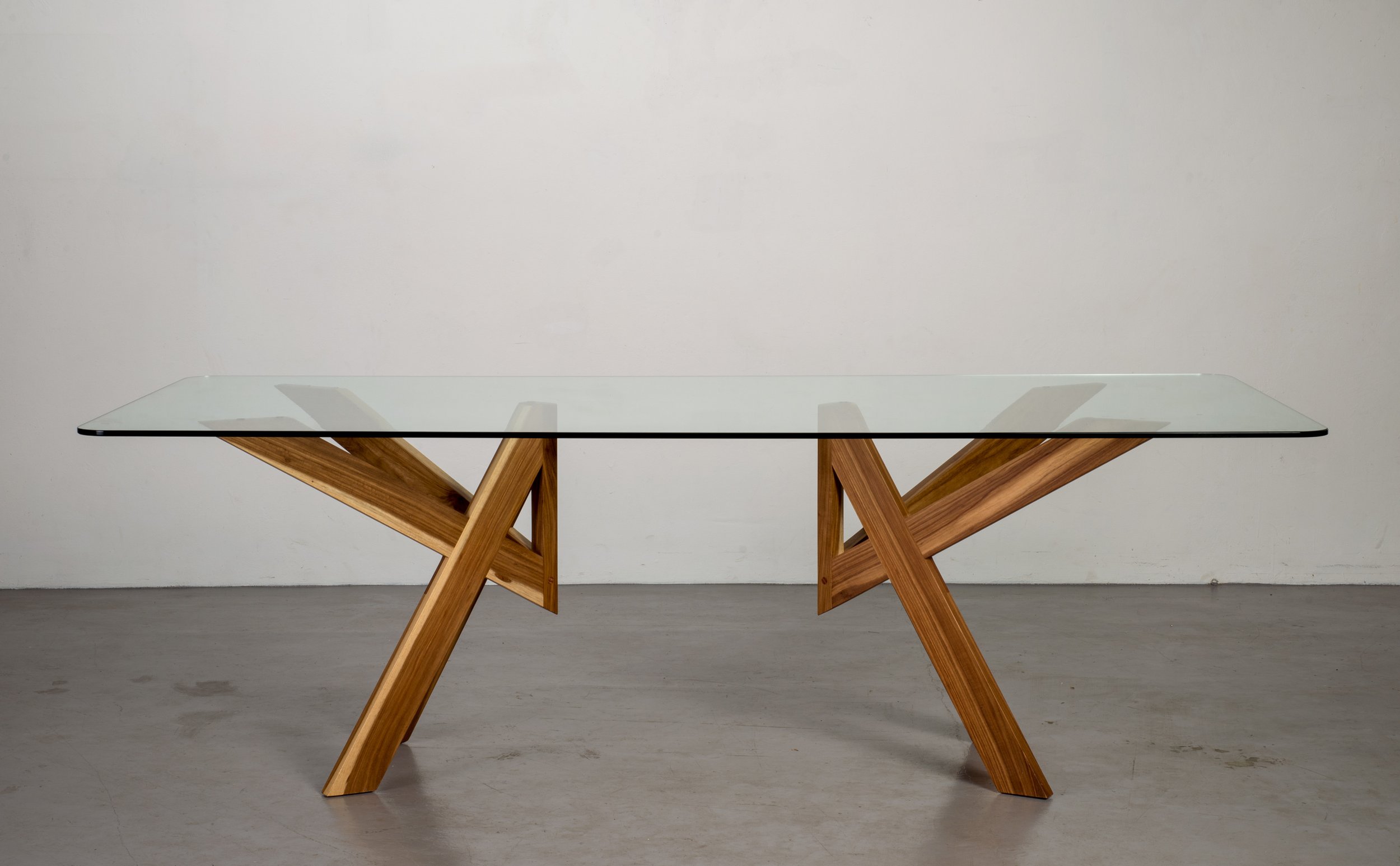 modern dining table with glass top and geometric angular wooden legs. unique design