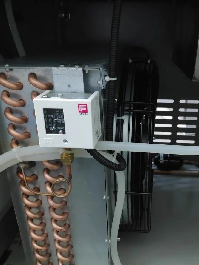 Close-up of the interior of an HVAC device showing copper refrigerant pipes, a digital control unit, and part of a black fan motor.