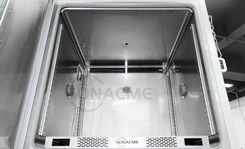 Interior of a stainless steel laboratory or industrial oven or sterilizer with ventilation holes and adjustable racks.