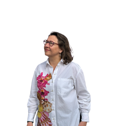 Femme portant une chemise blanche avec un motif floral rose et jaune, lunettes, cheveux gris, souriant, fond blanc.