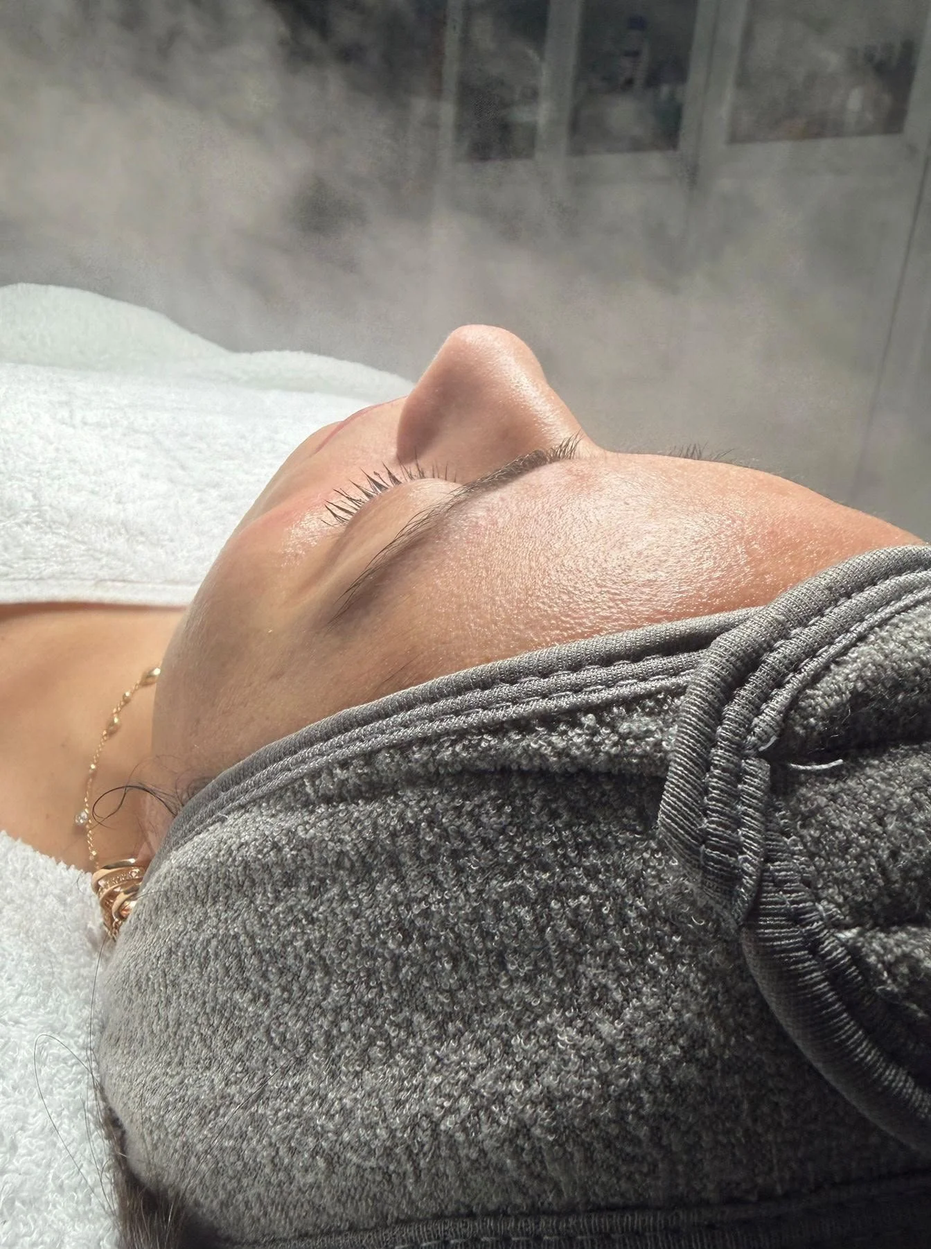 Nahaufnahme eines liegenen Gesichts mit geschlossenen Augen in einem Spa- oder Wellnessbereich.